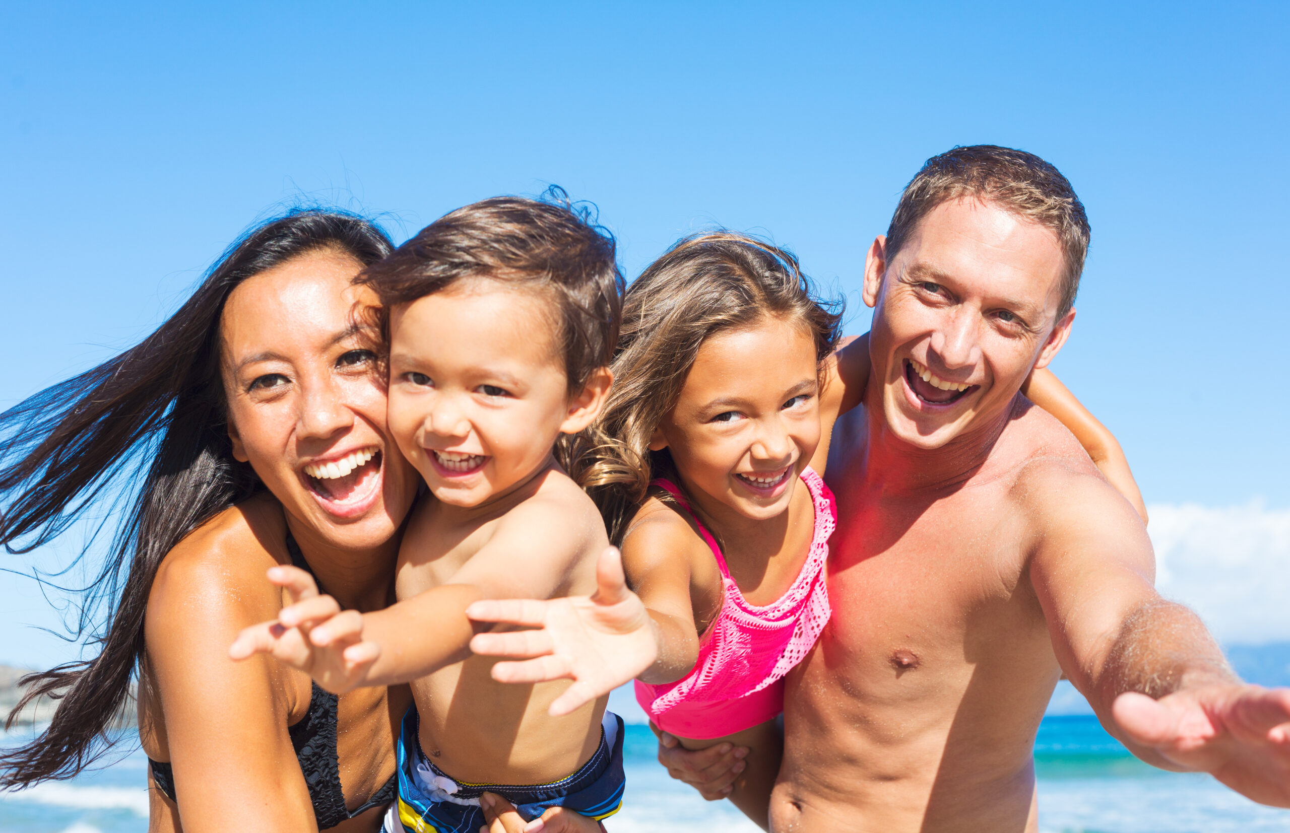 Happy Mixed Race Family of Four Playing and Having Fun on the Beach